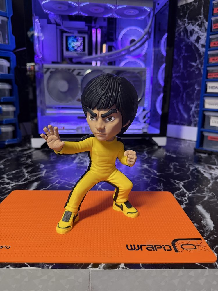 Bruce Lee figure in a yellow tracksuit on a work mat